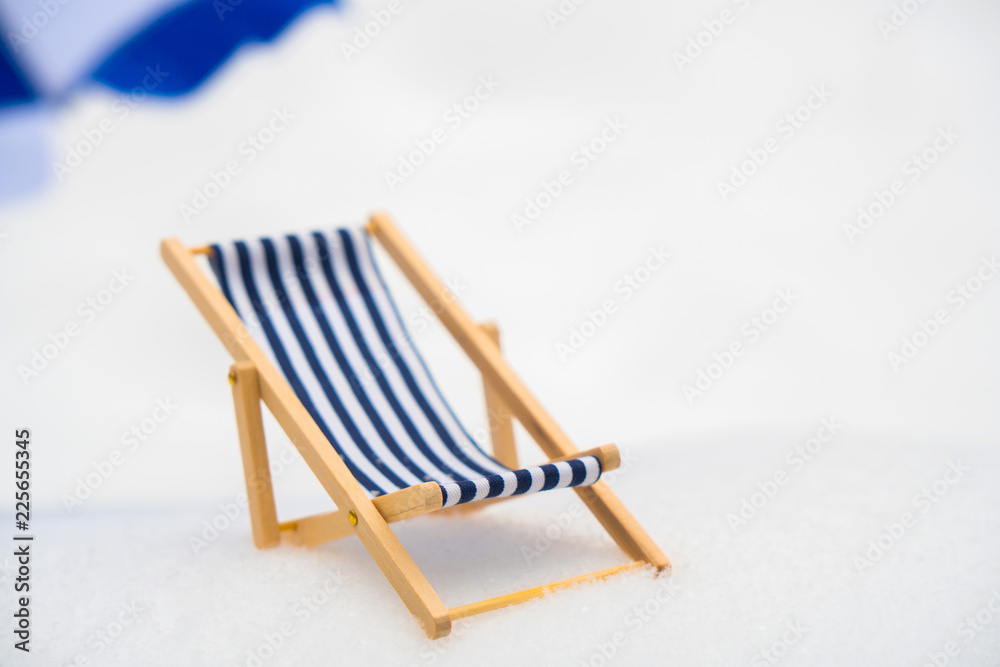 Blue, wooden, striped wooden beach chair in the snow.