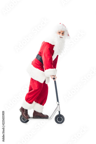 happy santa claus in costume riding on kick scooter isolated on white background