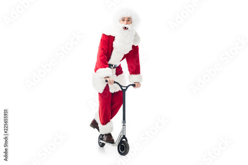 shocked santa claus in costume riding on kick scooter isolated on white background