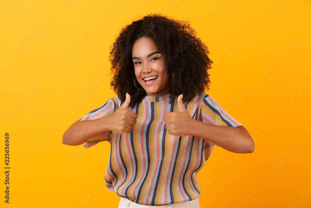 Young african cute girl posing isolated over yellow background make thumbs up gesture. Young african cute girl posing isolated over yellow background make thumbs up gesture.
