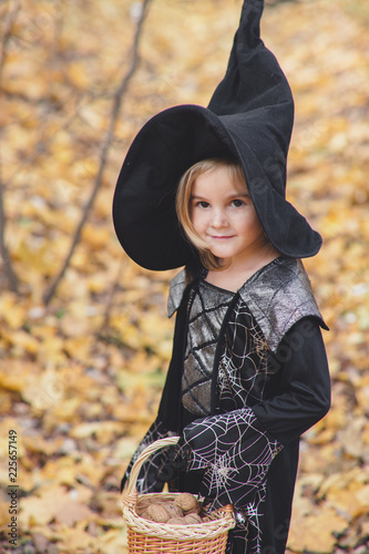 Beautiful girl witch. little girl in which costume celebrate Halloween outdoor and have a fun.