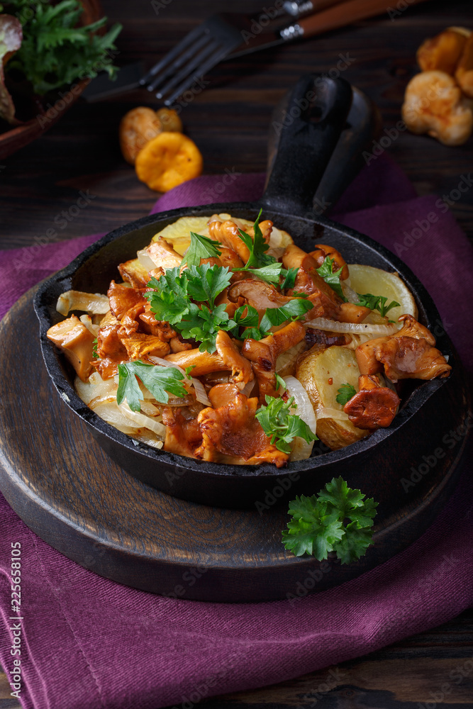 Fried chanterelle mushrooms with potatoes in frying pan on dark background. Fried chanterelle mushrooms with potatoes in frying pan on dark background.