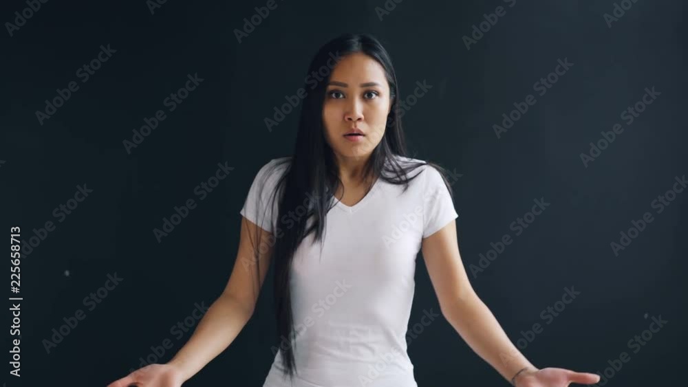 Portrait of surprised Asian woman looking at camera raising eyebrows, opening mouth and gesturing expressing astonishment. People, emotions and reactions concept. Portrait of surprised Asian woman looking at camera raising eyebrows, opening mouth and gesturing expressing astonishment. People, emotions and reactions concept.