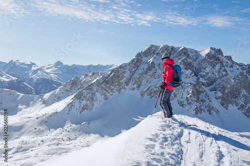 Male ski tourer enjoying the view on a summit in the alps