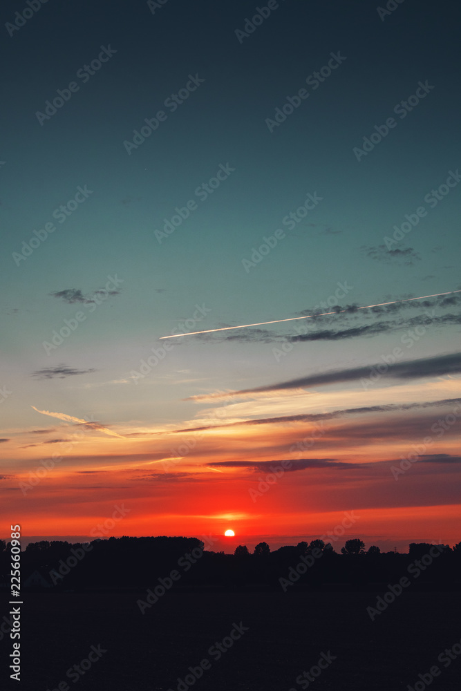 Summer sunset sky with orange bright colors and blue tones. Germany countryside landscape. Brunswick, Lower Saxony in Germany