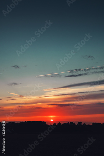 Fototapeta Naklejka Na Ścianę i Meble -  Summer sunset sky with orange bright colors and blue tones. Germany countryside landscape. Brunswick, Lower Saxony in Germany