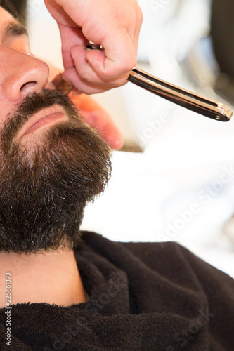Young Bearded Man Getting Beard Haircut By Barber in barbershop