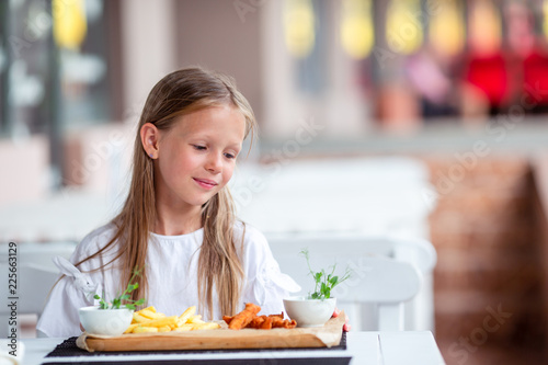 Adorable little girl having lunch at outdoor cafe