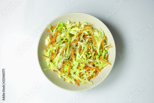 Cabbage salad with carrots, on a plate on a white background
