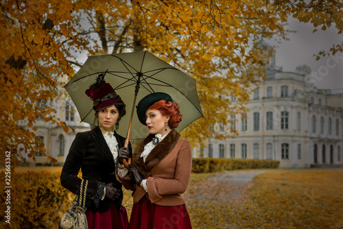 Two beautiful women with umbrellas in the park