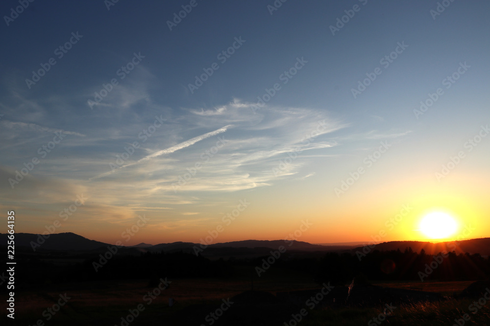 A beautiful sunset in czech lands with blue sky with small cloudies and dark land. Blue sky and dark meadows and incredible sun with sunshine A beautiful sunset in czech lands with blue sky with small cloudies and dark land. Blue sky and dark meadows and incredible sun with sunshine