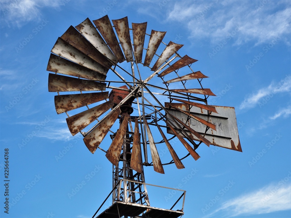 Old rusty metal wind pump blades against a blue sky