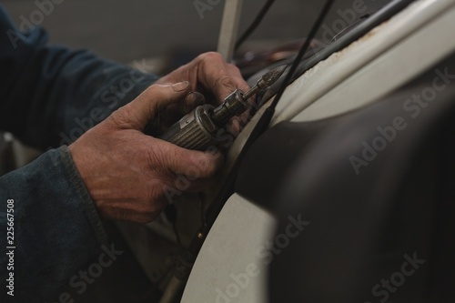 Male mechanic using mini drill machine