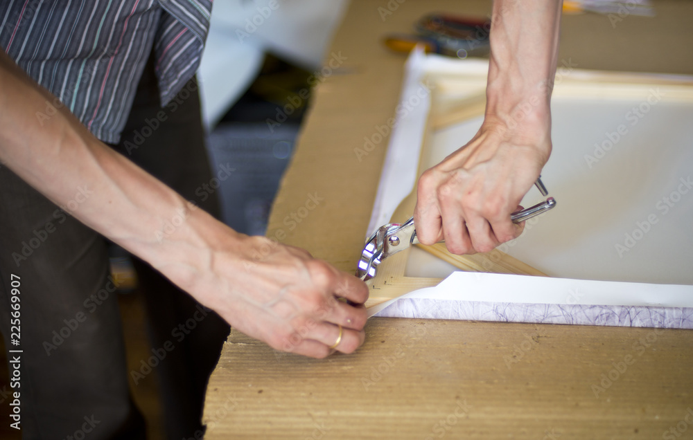 hands stretching the canvas on the stretcher hands stretching the canvas on the stretcher