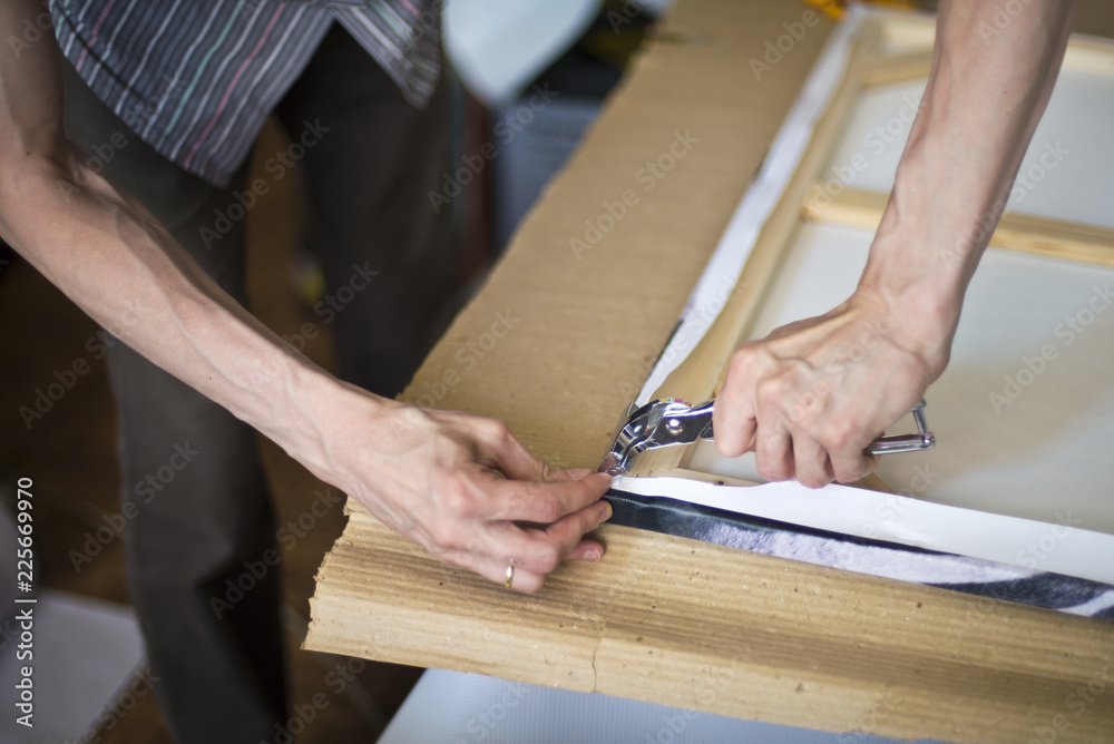 hands stretching the canvas on the stretcher hands stretching the canvas on the stretcher