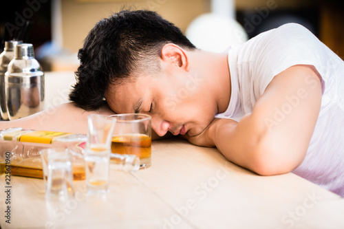 Young male drunker sleeping on bar counter