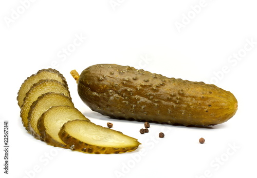 Whole and sliced salted cucumber with black peppercorns close-up on a white background