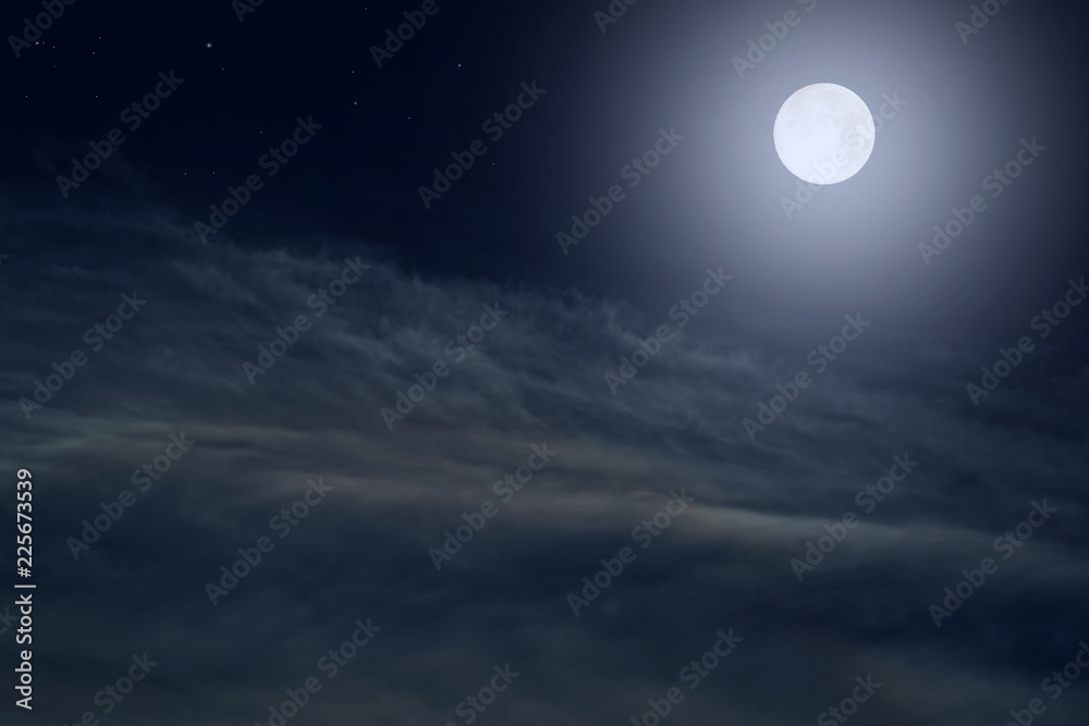 The full moon between the clouds in the night sky