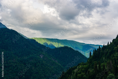 Caucasus mountains with woodland and clouds in summer