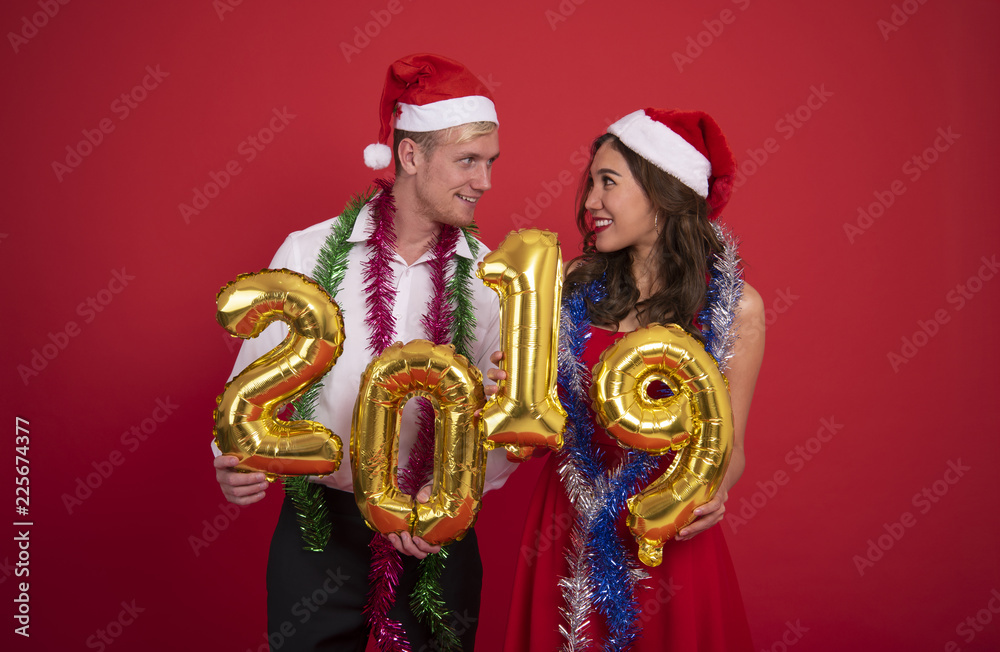 Portrait young couple carrying gold colored numbers 2019 on red background. celebration christmas and happy new year concept.