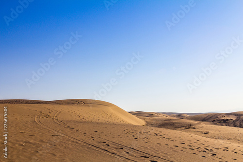 Sand dunes in the Maranjab desert, near Kashan, Iran, at sunset, with the path of feet and tires visible on the dunes. maranjab desert is one of the main landmarks of the region..