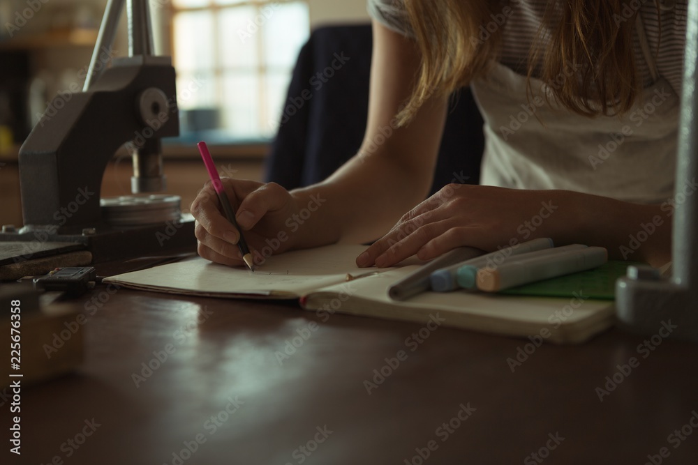Jewelry designer writing on a register in workshop Jewelry designer writing on a register in workshop