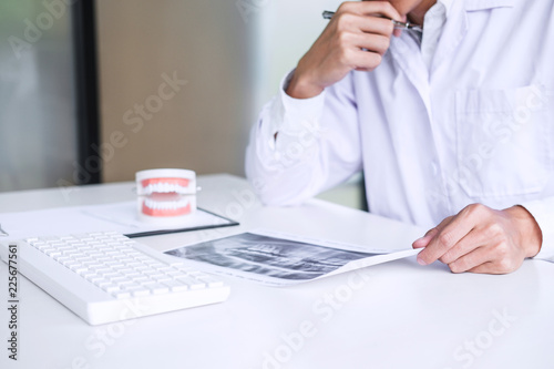 Male doctor or dentist writing report working with tooth x-ray film  model and equipment used in the treatment of dental and dentistry at workplace