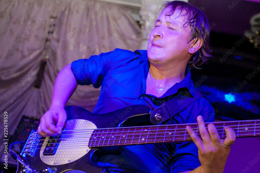 Obraz premium Musician plays bass guitar on stage in neon light