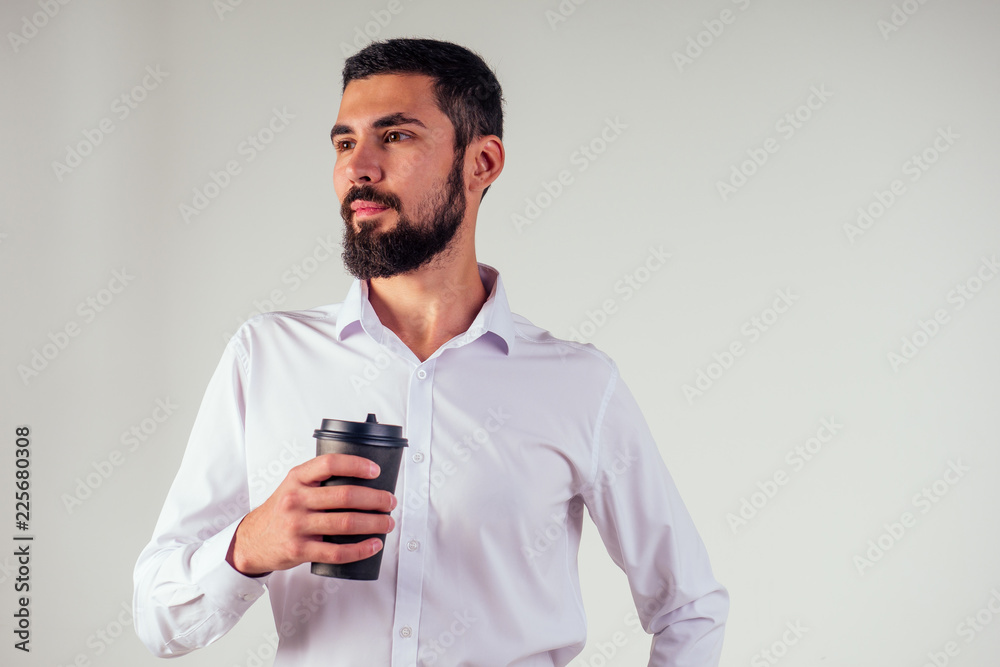 handsome Arab Sheikh businessman black beard in a white shirt and black trousers holding a plastic paper cup and drinking coffee on white background studio shot handsome Arab Sheikh businessman black beard in a white shirt and black trousers holding a plastic paper cup and drinking coffee on white background studio shot