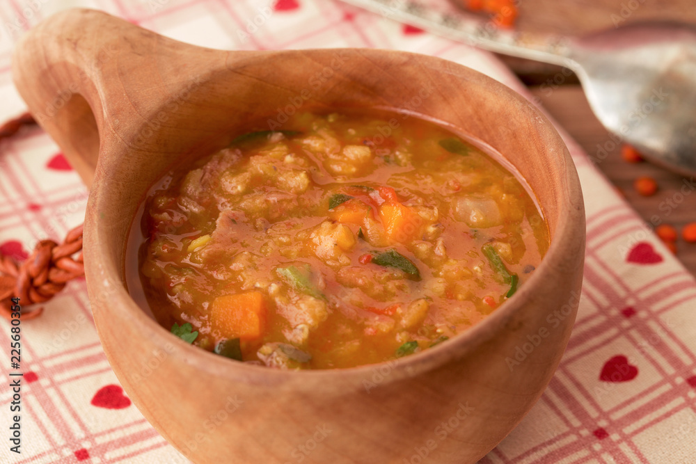 Red lentil soup with meat and vegetables in a wooden bowl Red lentil soup with meat and vegetables in a wooden bowl