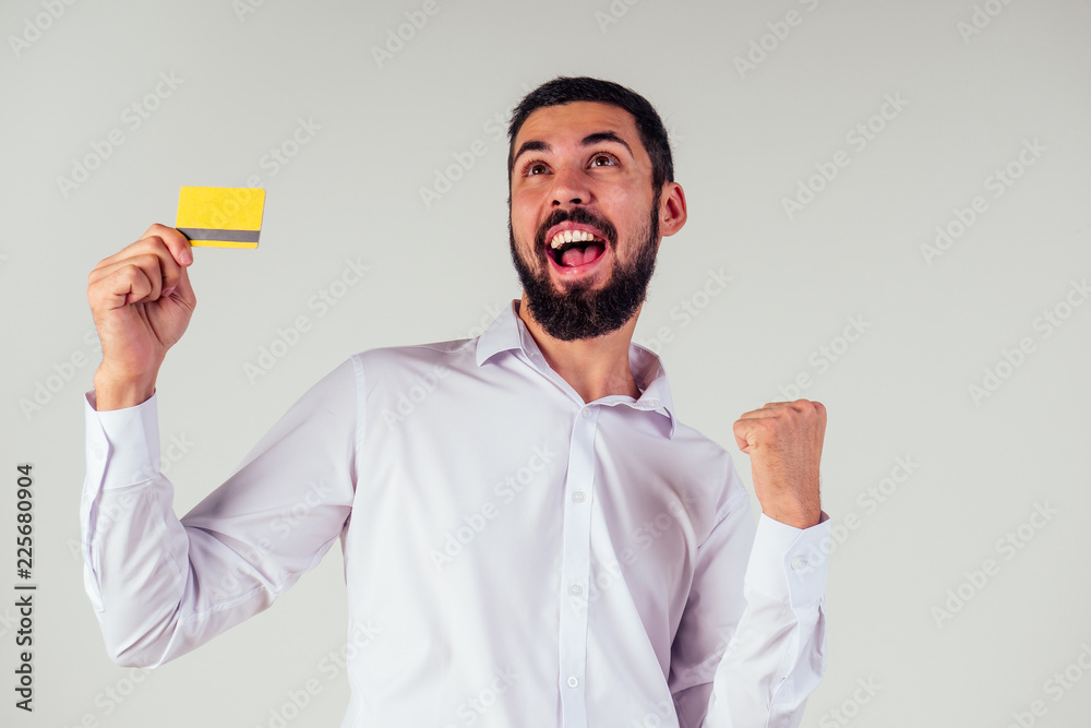 business man in a white shirt holding yellpw credit card . Looking at camera, smiling . black friday sale and spend money concept