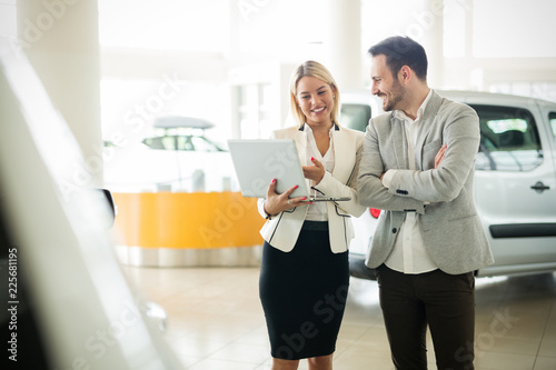 Professional salesperson during work with customer at car dealership.