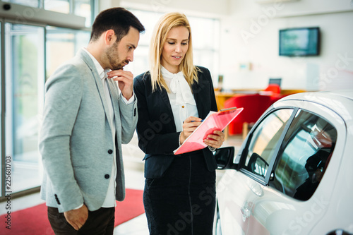 Young female car sales consultant working in showroom