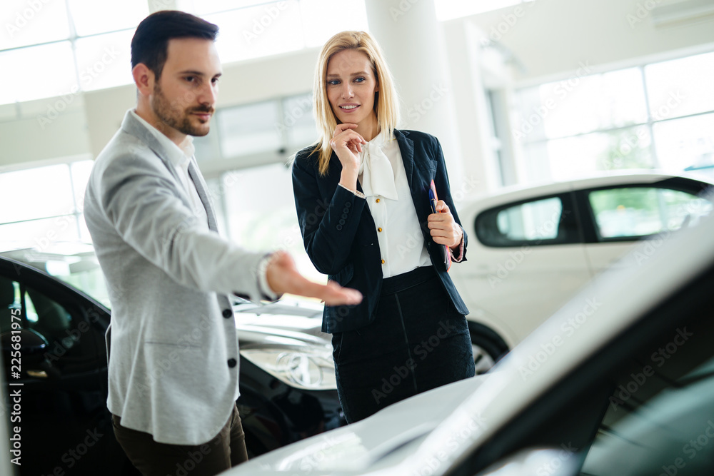 Dealer showing a new car model to the potential customer