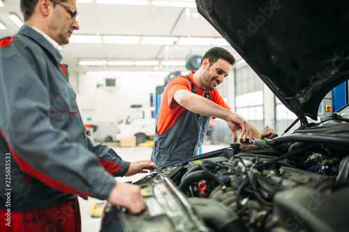 Car mechanics working at automotive service center © NDABCREATIVITY