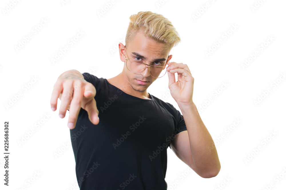 handsome trendy young guy in a black shirt on a white background. straightens glasses and points with your finger handsome trendy young guy in a black shirt on a white background. straightens glasses and points with your finger