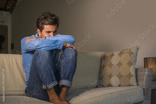 young attractive and handsome sad latin man sitting tired and depressed at home sofa couch feeling overwhelmed and worried suffering depression crisis and anxiety