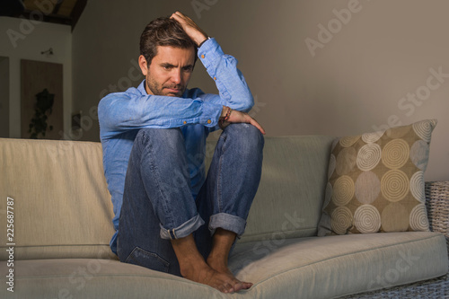 young attractive and handsome sad latin man sitting tired and depressed at home sofa couch feeling overwhelmed and worried suffering depression crisis and anxiety