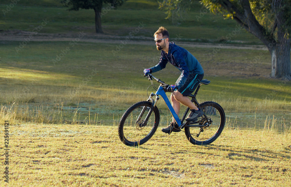 A cyclist rides the hills, Beautiful portrait of a guy on a blue bicycle A cyclist rides the hills, Beautiful portrait of a guy on a blue bicycle