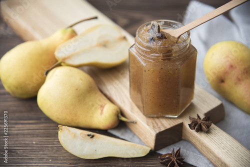  jar of pear jam and fresh pears on a dark wooden background