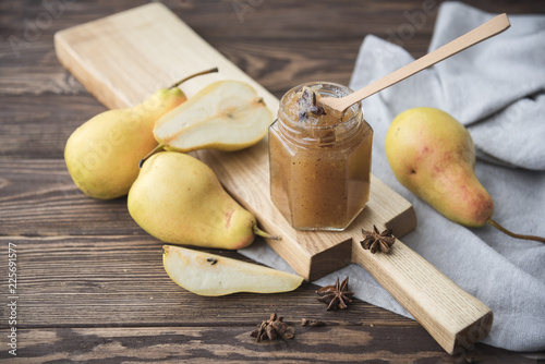  jar of pear jam and fresh pears on a dark wooden background