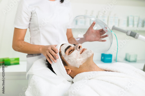 Facial beauty treatment of good looking man with oxygen mask at cosmetic beauty salon.