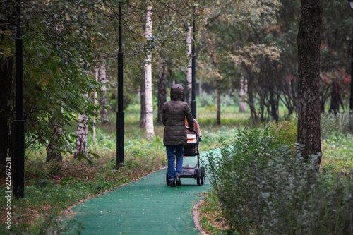 Woman with stroller is walking n the autumn park
