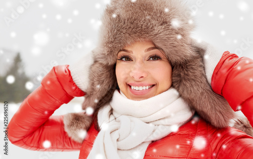 people, season and leisure concept - happy woman in winter fur hat outdoors