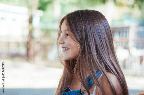 Little girl cheerful, laughs and sits on a bench in the park summer Free Download Little girl cheerful, laughs and sits on a bench in the park summer - GFXLoad