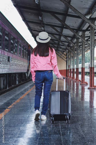 Woman traveler tourist walking with luggage at train station. Active and travel lifestyle concept