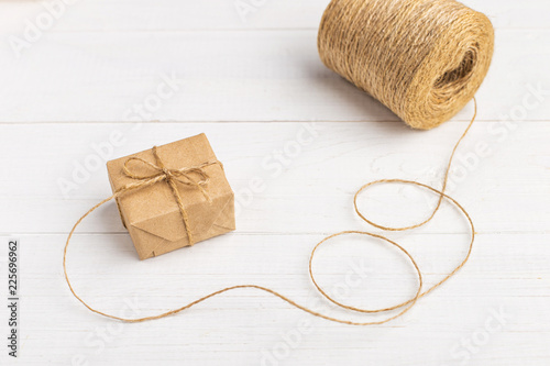 Gifts from Kraft paper on a white table with threads.