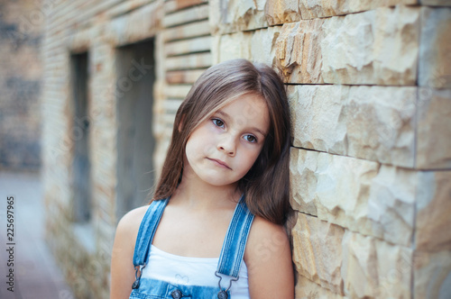 Model little beautiful girl with long hair, street fashion near the wall on a summer © QKon Studio