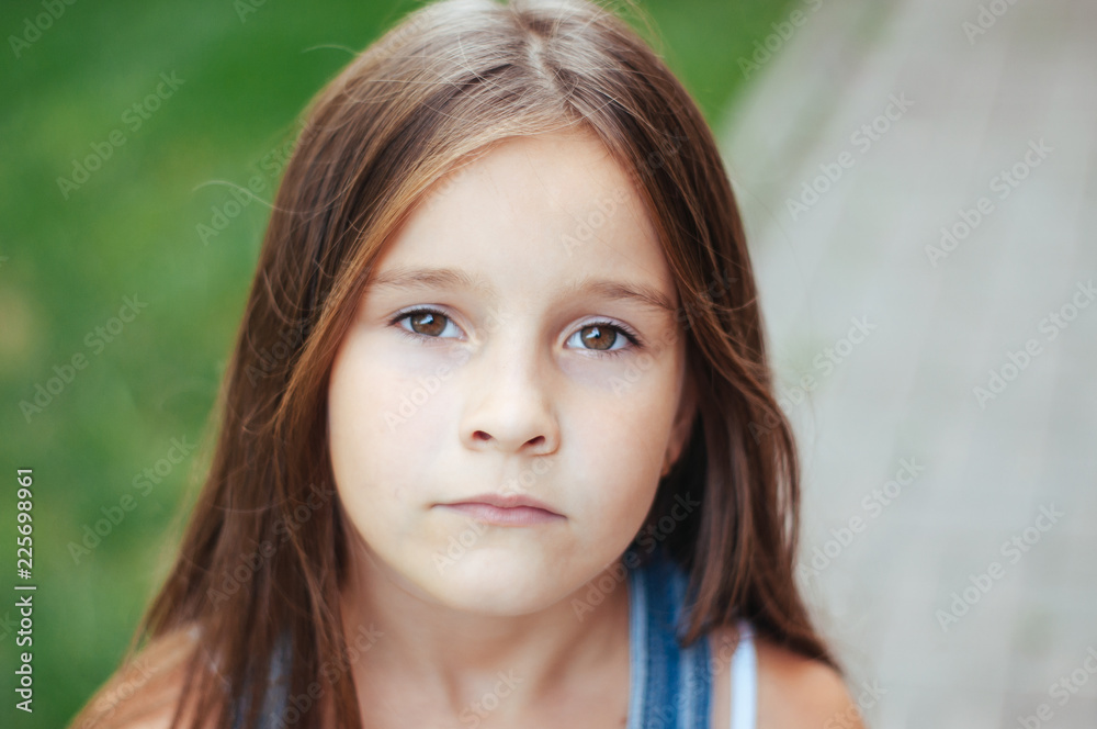 Model little beautiful girl with long hair, street fashion near the wall on a summer Model little beautiful girl with long hair, street fashion near the wall on a summer