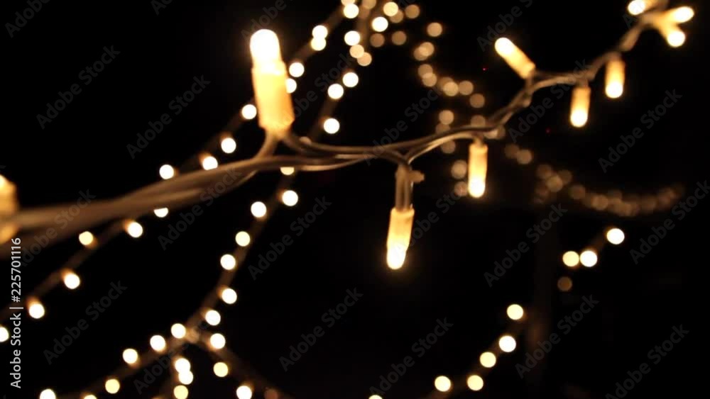 A short clip of fairy lights in a dark studio and the camera moving close to a string of light, while showing more lights and reflections in the background.